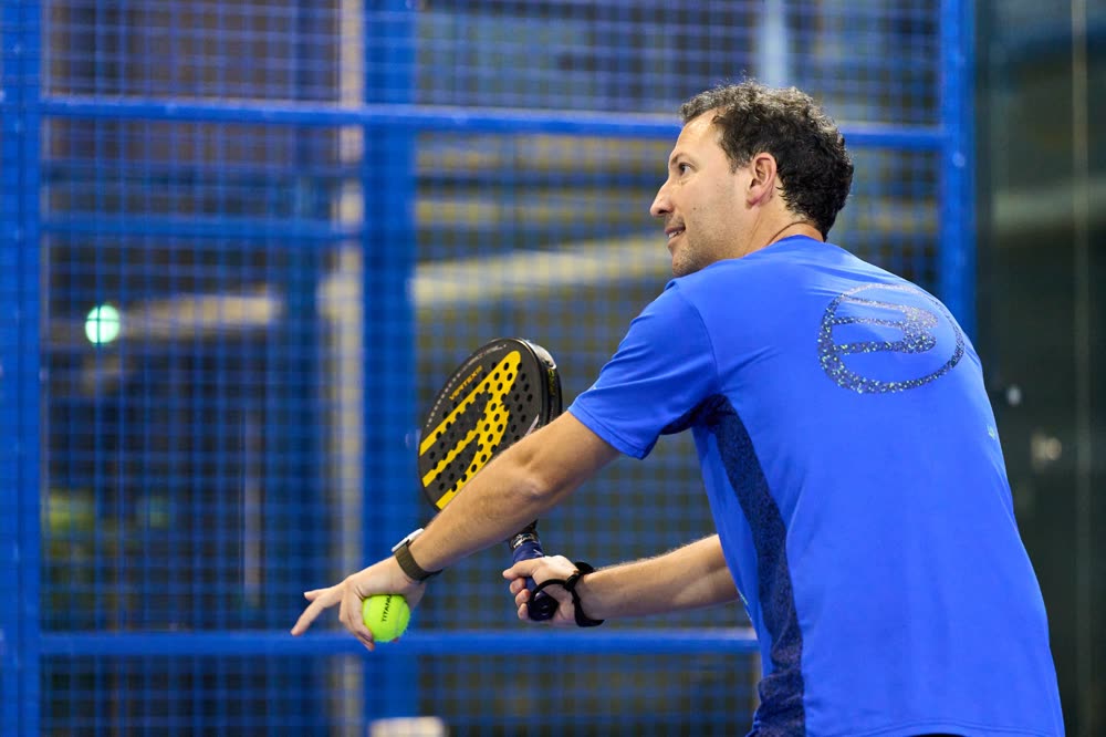 Carlos Ferretti dando clase de pádel en cancha indoor